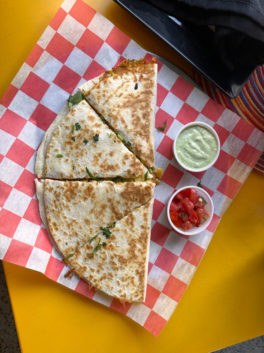 Quesadilla cut into wedges with salsa and crema